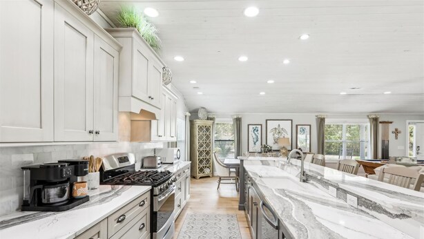 A spacious kitchen with white cabinetry, a large island, and a view to the dining area.