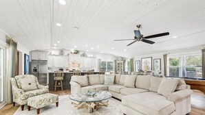 A spacious living room with a large sectional sofa, a glass coffee table, and a ceiling fan.