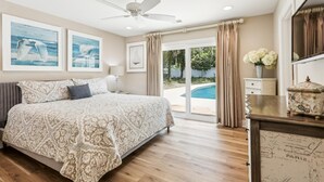 A bedroom with a large bed, a ceiling fan, and a view of a swimming pool.