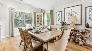 A dining room with a wooden table, chairs, and a rustic decor including a wooden sculpture and framed artwork.