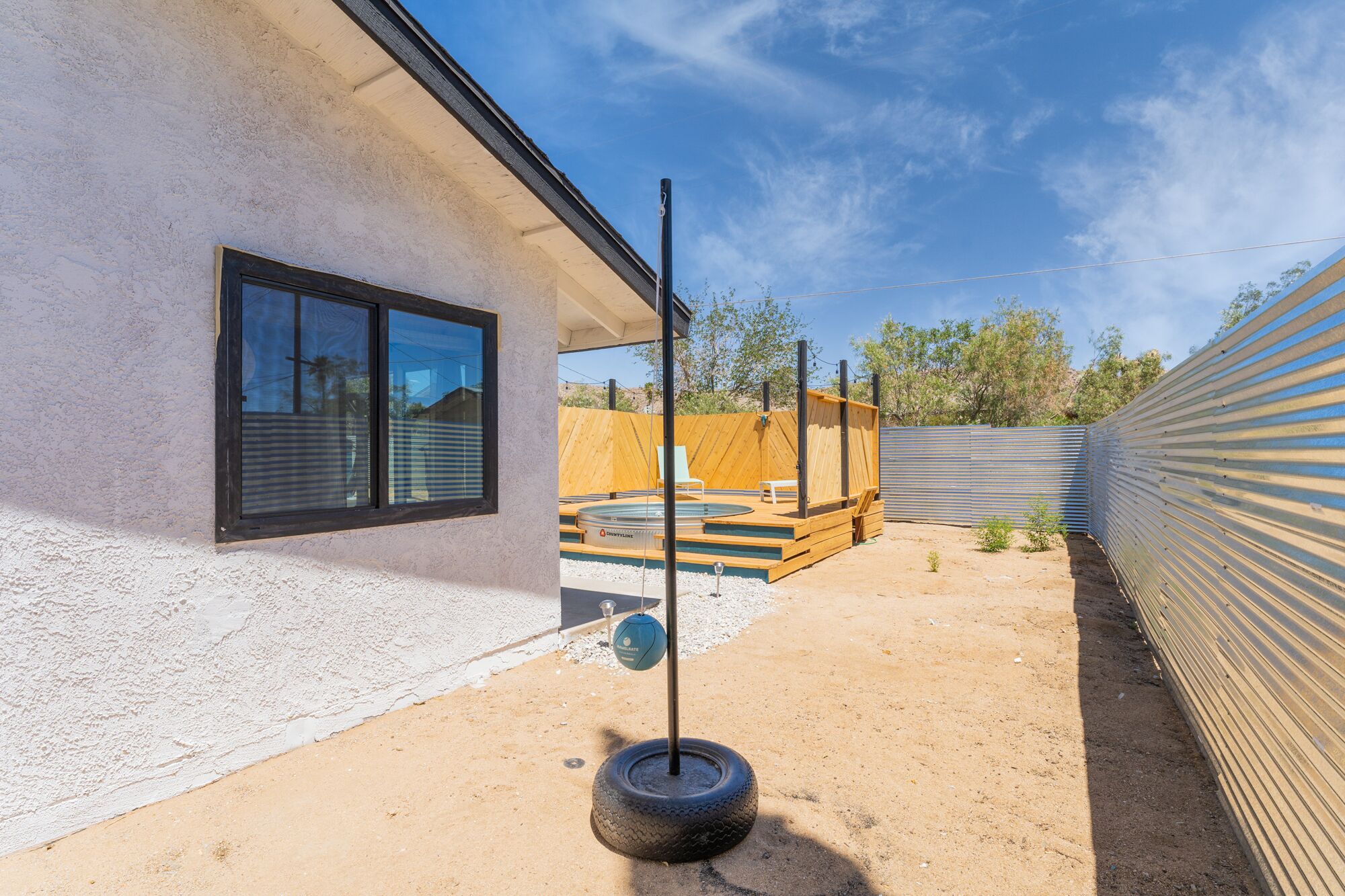 A modern house with a large window, a wooden deck, and a swimming pool.