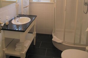 A bathroom with a white sink, black countertop, white toilet, and a glass shower enclosure. - Gutshaus Zicker in Garz (Garz)