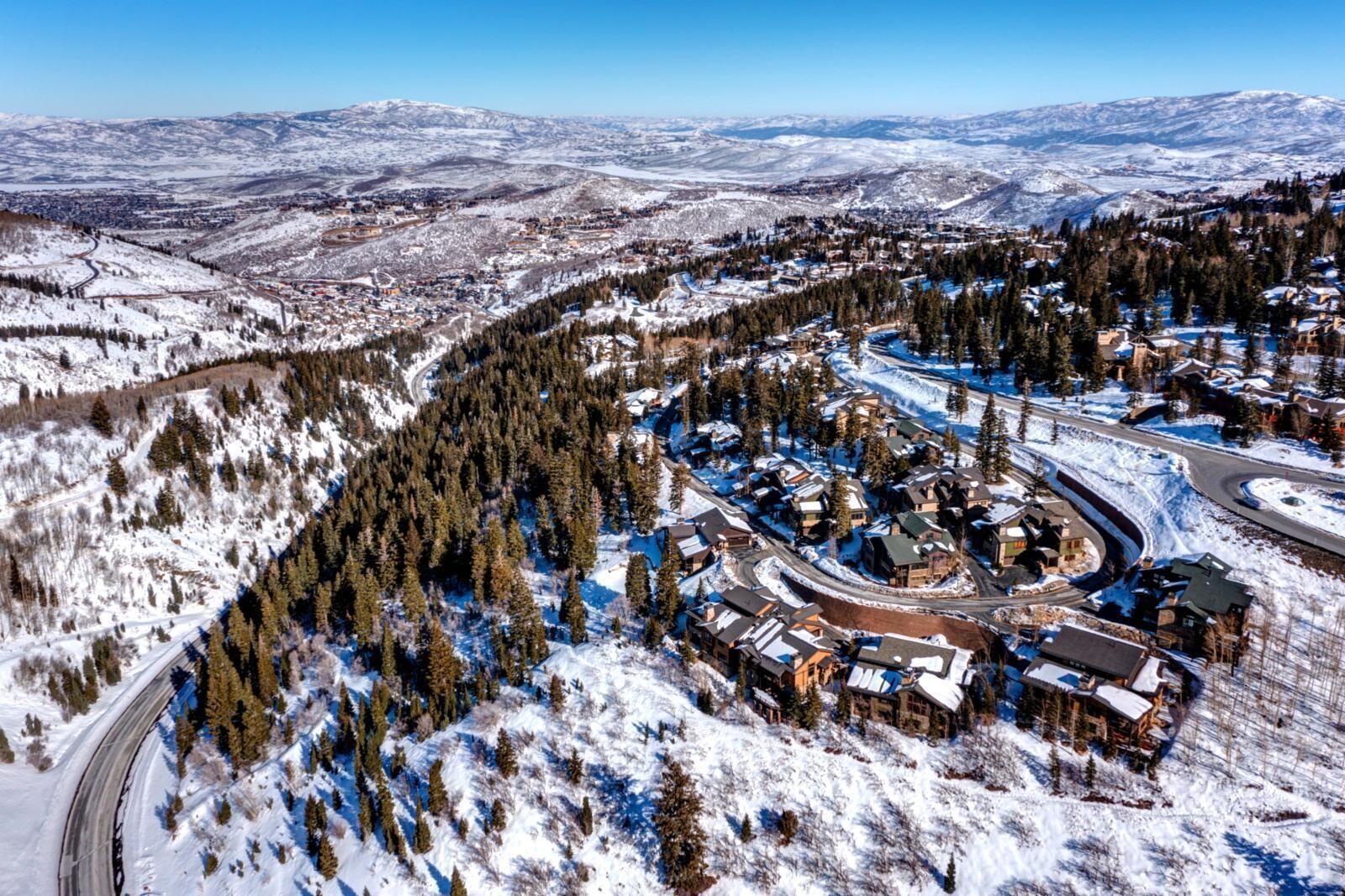 A snow-covered town with a winding road, buildings, and a mountainous backdrop.