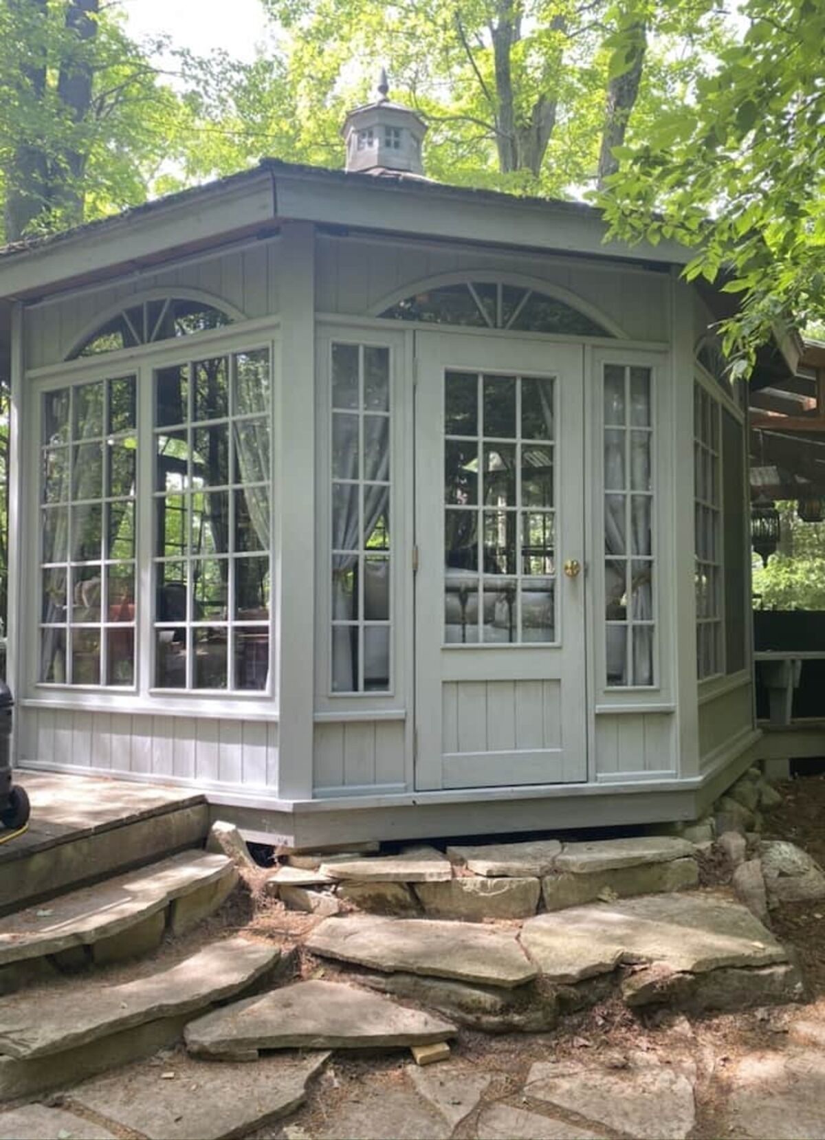 A covered outdoor area with stone steps leading up to a door, surrounded by trees.