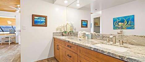 A modern bathroom with a large mirror, wooden cabinets, and artwork on the walls.
