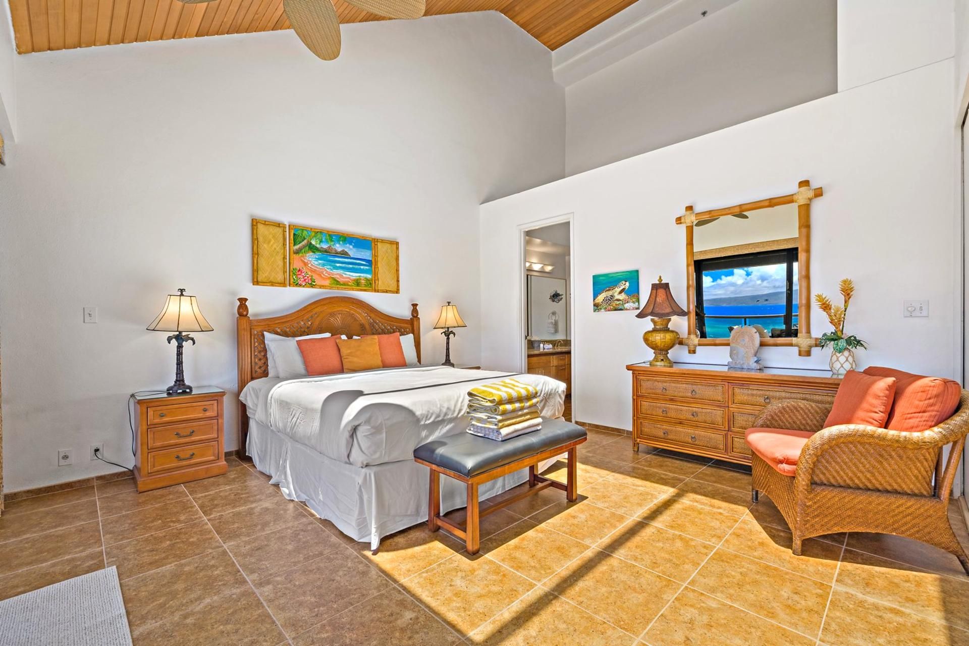 A bedroom with a bed, bedside tables, a bench, a dresser, a chair, and artwork on the walls.
