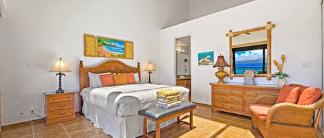 A bedroom with a bed, bedside tables, a bench, a dresser, a chair, and artwork on the walls.
