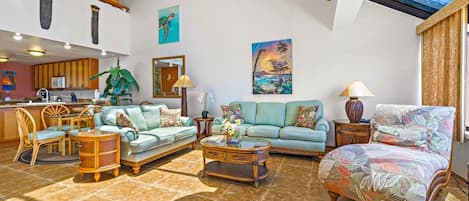 A spacious living area with a high ceiling, a dining area, and a kitchen.