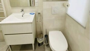 A small, clean bathroom with a white sink, mirror, and toilet. - Appât T2 en Rdc à 50 Mètres de la Plage (Saint Palais sur Mer)