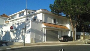 A two-story building with a white facade, a tiled roof, and a parked car in the driveway. - Appât T2 en Rdc à 50 Mètres de la Plage (Saint Palais sur Mer)