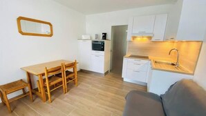 A compact kitchen with a dining area, a built-in oven, and a sink. - Appât T2 en Rdc à 50 Mètres de la Plage (Saint Palais sur Mer)