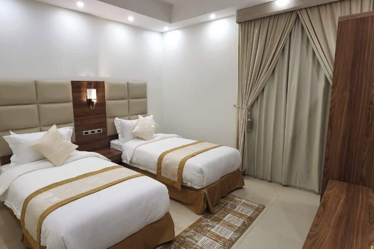 A hotel room with two beds, a wooden headboard, a nightstand, and a large window with curtains.