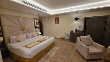 Quarto de hotel moderno com uma cama grande, área de estar e guarda-roupa.