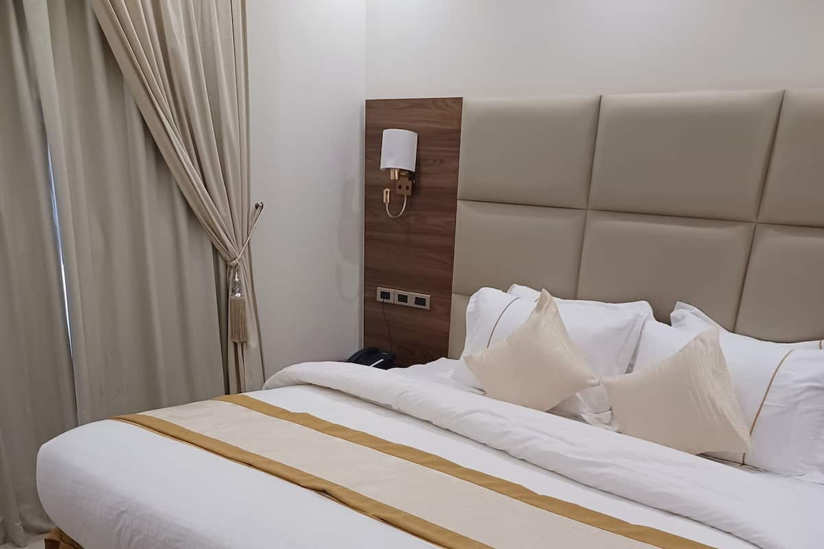 A neatly made bed with a beige headboard, white bedding, and a brown accent strip.