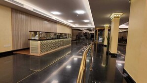 Um hall de hotel espaçoso com uma recepção, divisória de vidro e piso polido.