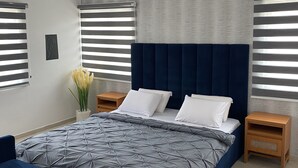 Une chambre moderne avec un grand lit, deux tables de chevet et une petite table d’appoint.