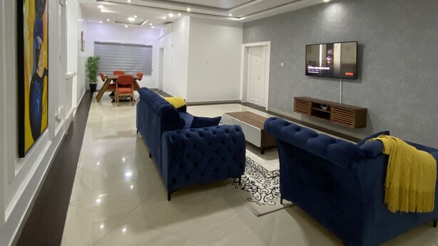 Un salon moderne avec un ensemble de canapés, un téléviseur à écran plat fixé au mur et un tapis décoratif.