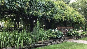 Un giardino rigoglioso con diverse piante, un muro in pietra e un pontile in legno.