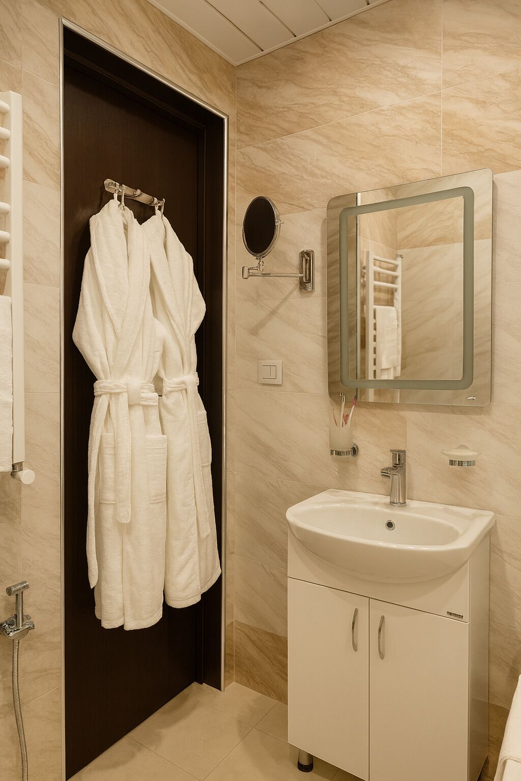 A bathroom with a white sink, a mirror, and a robe hanging on the wall.