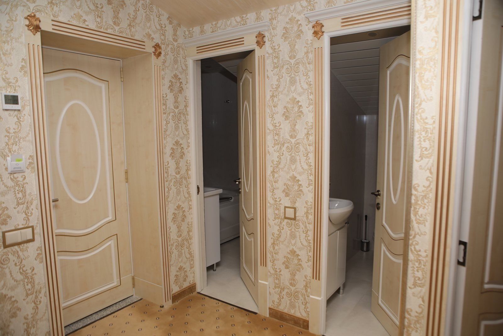 Un pasillo con puertas ornamentadas que dan a un baño.