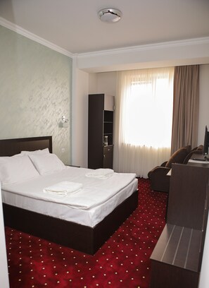 Cozy retreat with a neatly made bed, desk, and wardrobe, perfect for a comfortable stay.