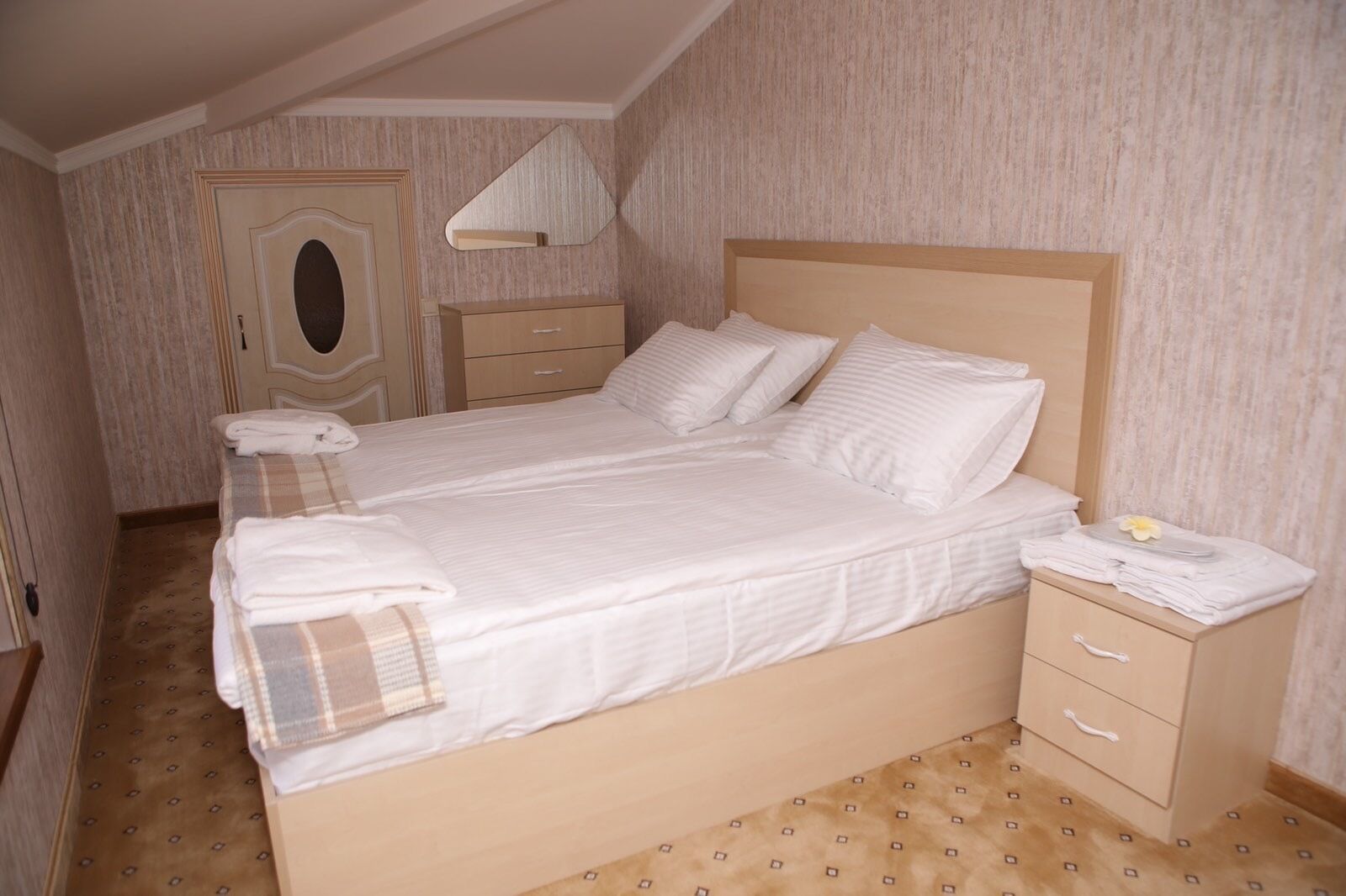 Un dormitorio con una cama grande, una mesita de noche, un armario y un espejo.