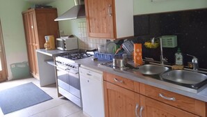 A kitchen with wooden cabinets, a gas stove, a dishwasher, and a double sink.