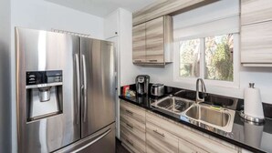 Een moderne keuken met roestvrijstalen apparatuur, een waterdispenser en een raam dat voor natuurlijk licht zorgt.