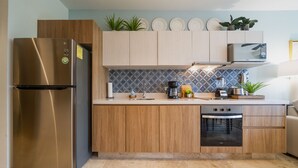 Una cocina moderna con refrigerador de acero inoxidable, armarios de madera, microondas y lavavajillas.