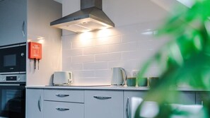 Une cuisine moderne avec des meubles blancs, un four à micro-ondes, un grille-pain et une couverture anti-feu.