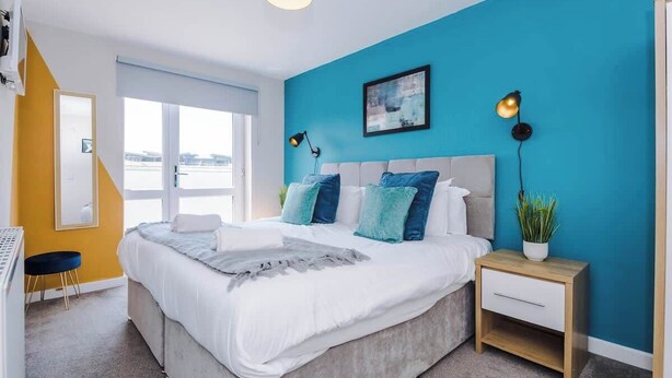 A modern bedroom with a large bed, a bedside table with a lamp, a window, and a view of the outside. - Hidden Gem within Central Chester - Great Location (Chester)