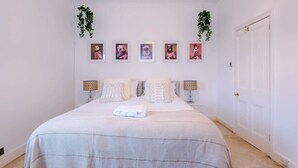 Quarto bem organizado com cama, mesas de cabeceira e quadros nas paredes.