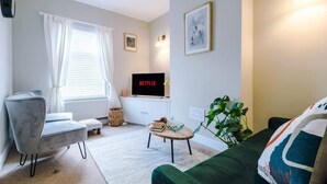 A living room with a sofa, a chair, a coffee table, a TV on a stand, and a plant. - 2BR Designer apartment for City Breaks in Chester. (Chester)