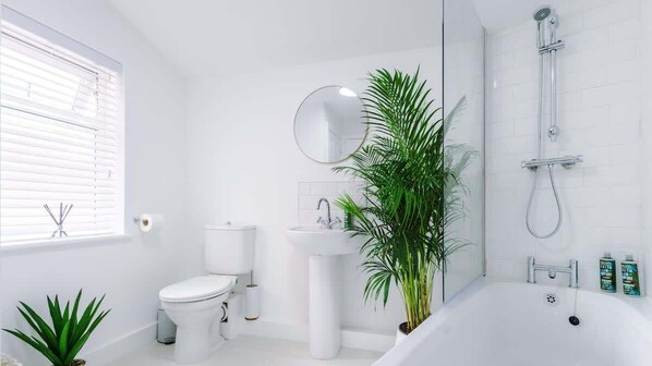 A modern bathroom with a toilet, sink, and bathtub.