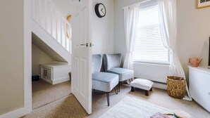 A cozy room with a staircase, a sofa, a small table, and a window with curtains. - 2BR Designer apartment for City Breaks in Chester. (Chester)
