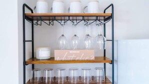 A shelf with white mugs, a Nespresso box, wine glasses, and clear tumblers. - 2BR Designer apartment for City Breaks in Chester. (Chester)
