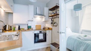 Eine kleine Küche mit weißen Schränken, einer Holz Arbeitsplatte, einem eingebauten Backofen und einer kleinen Mülltonne.