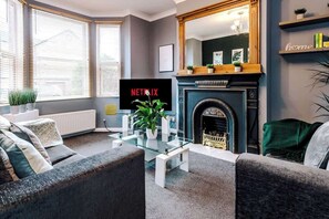 A living room with a fireplace, a glass coffee table, and a sofa. - Spacious Modern Chester Home - Great Location (Chester)