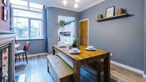 Un coin repas avec une table en bois dressée pour quatre personnes, un banc et une vue sur la cuisine.