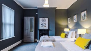 Une chambre d’hôtel avec deux lits, une cheminée et des œuvres d’art aux murs.