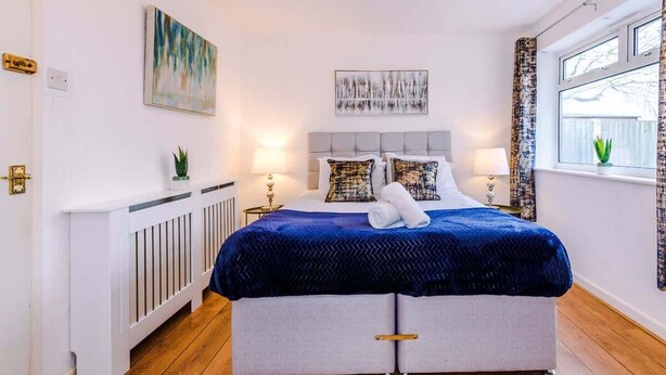 A bedroom with a bed, two bedside tables, a window with curtains, and a radiator. - Spacious 4 Bedroom Chester Home with parking. (Chester)