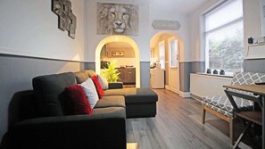 A modern living room with a sectional sofa, a wooden bench, and a view into the kitchen.