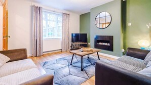 A living room with a sofa, a coffee table, a TV, and a fireplace.