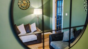 A room with a bed, a sofa, a lamp, and a clock on the wall.