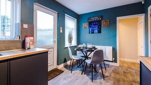 A modern kitchen with a dining area, a coffee menu sign, and a neon sign indicating happy hour.