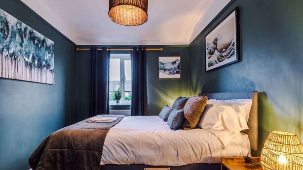 A bedroom with a bed, a bedside lamp, and artwork on the walls.