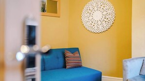A room with a blue sofa, a patterned pillow, and a decorative wall piece.