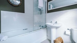 A modern bathroom with a glass-enclosed shower, a white sink, and a round wall clock.