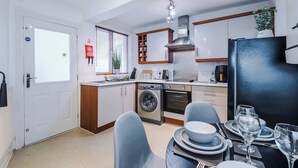 A compact kitchen with a washing machine, a stove, and a dining area with a table set for two.