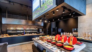A modern buffet setup with a variety of food items and a bar area in the background. - Wyndham Garden Sapporo Odori (Sapporo)